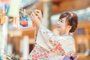 Kimono-clad woman decorating tanzaku strips for the Tanabata Festival.