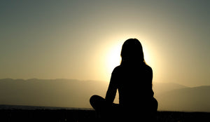 A woman doing zen meditation under sunset